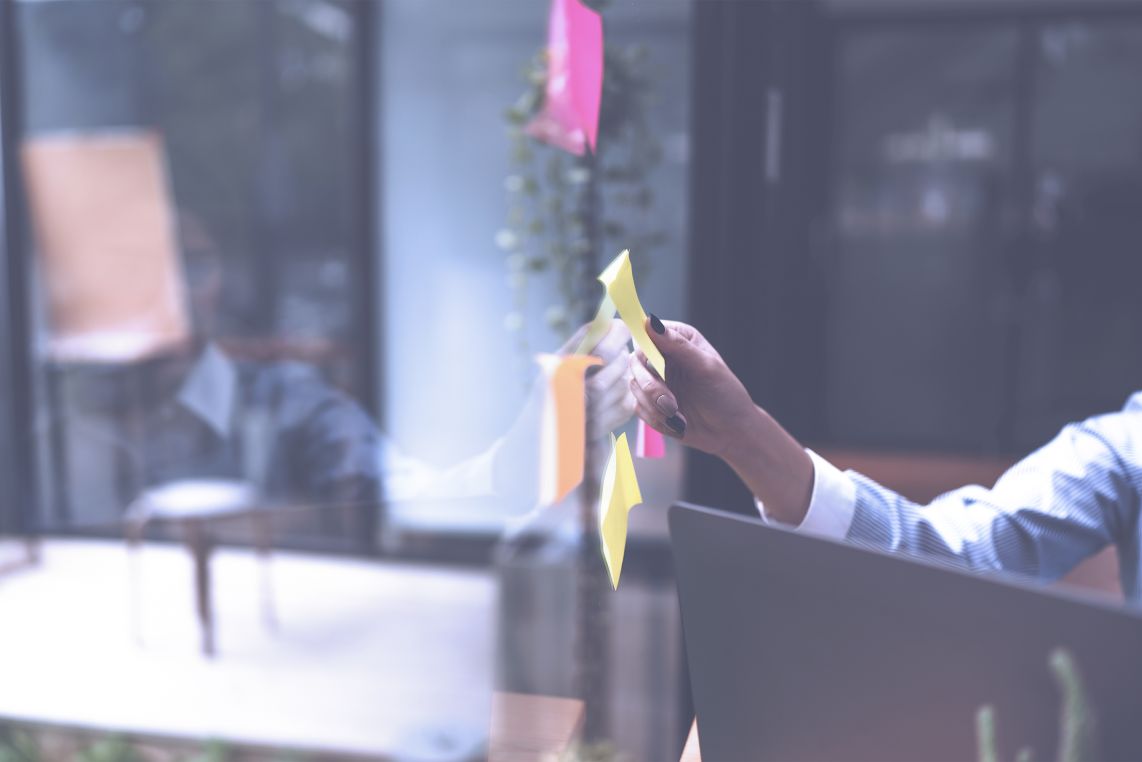 colleagues hands putting sticky note on a window