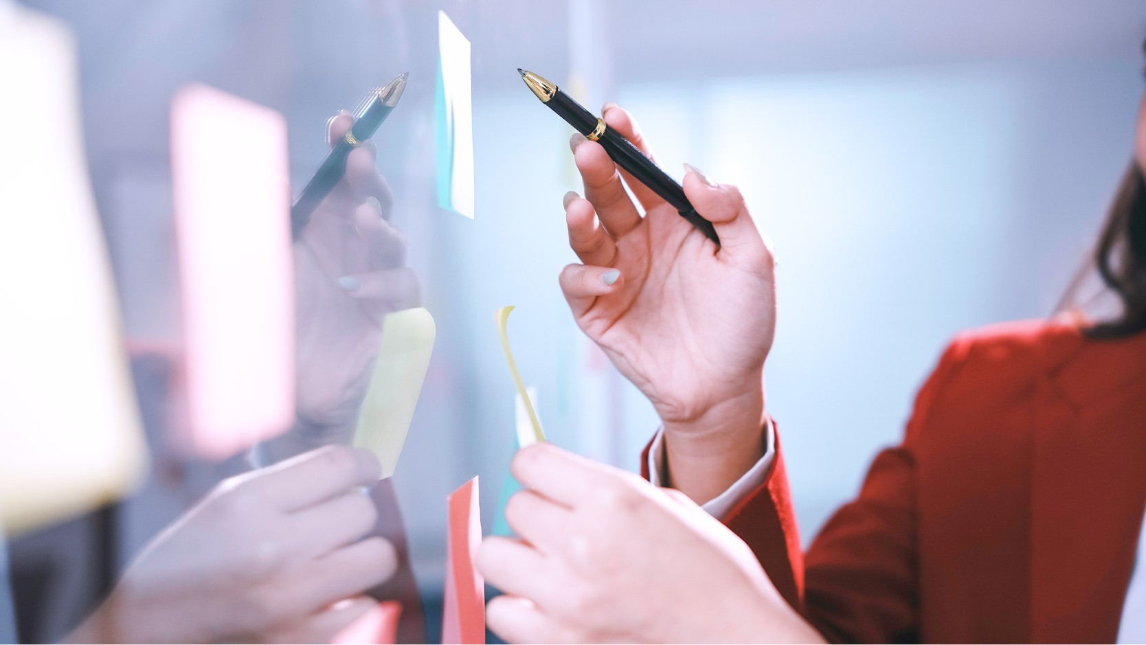 colleagues hands putting sticky note on a window