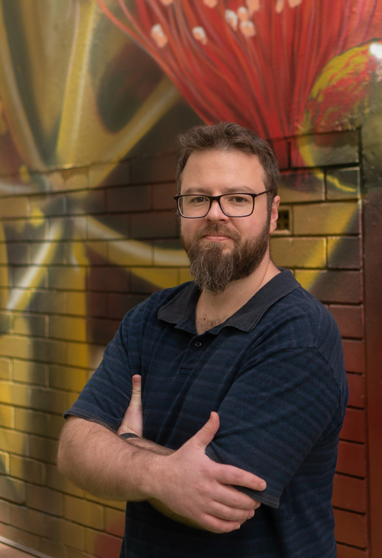 Image of man against illustrated-mural wall.