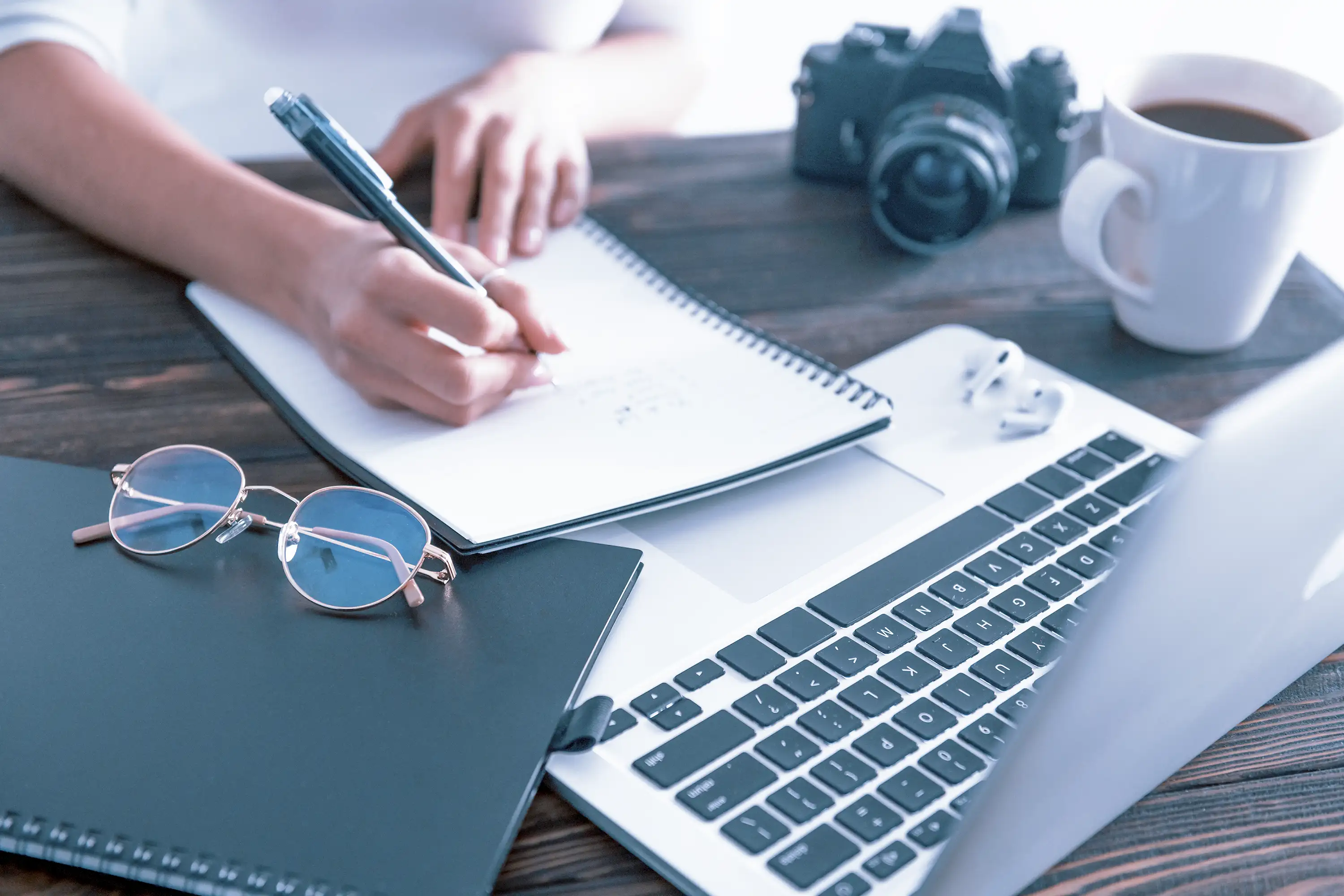 Woman writing notes with a laptop on a work table