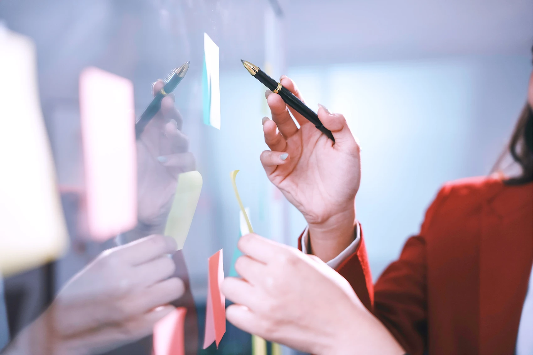 Close up of colleagues hands with sticky notes on a wall at a workshop. 