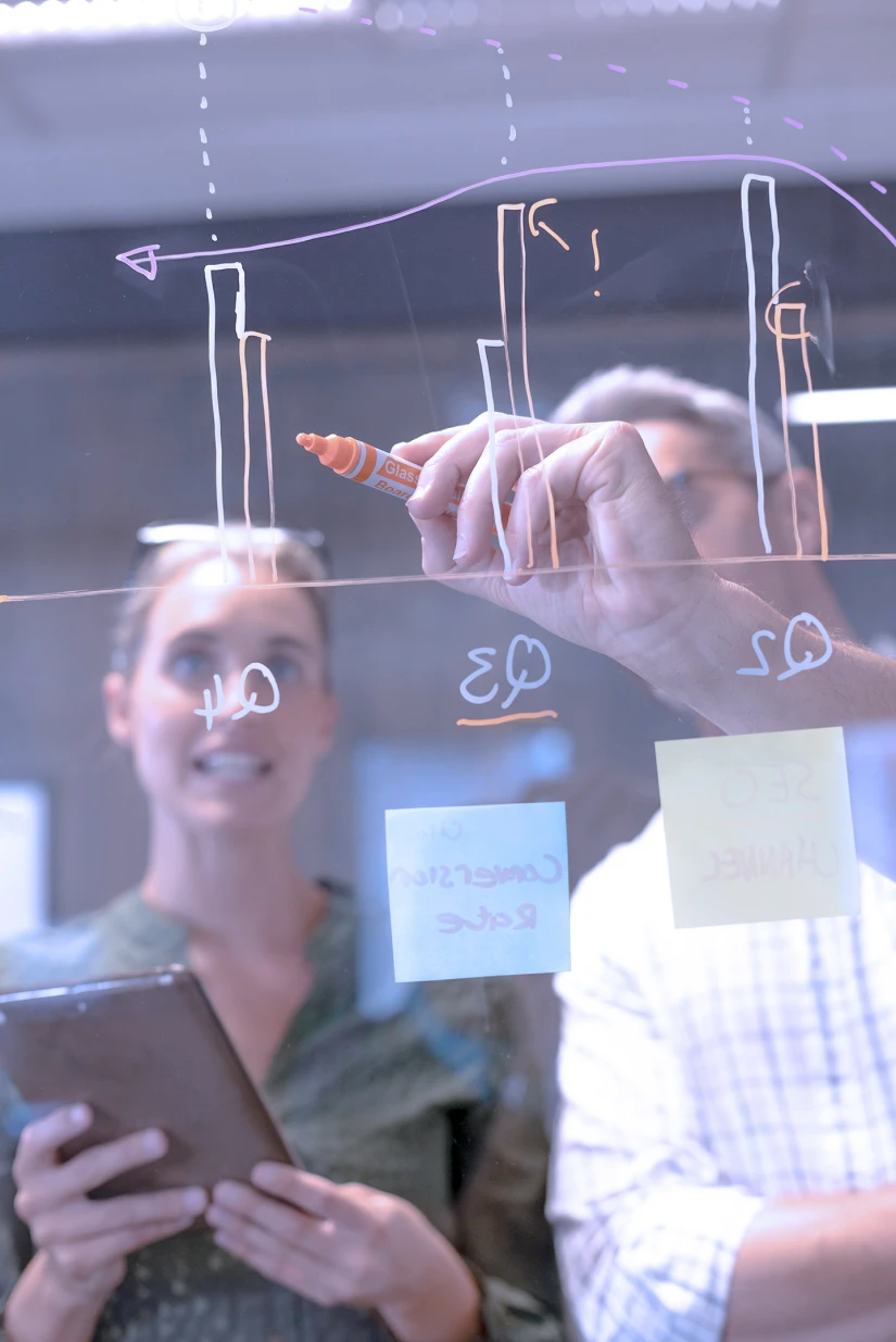 Colleagues drawing diagrams on a window at a workshop