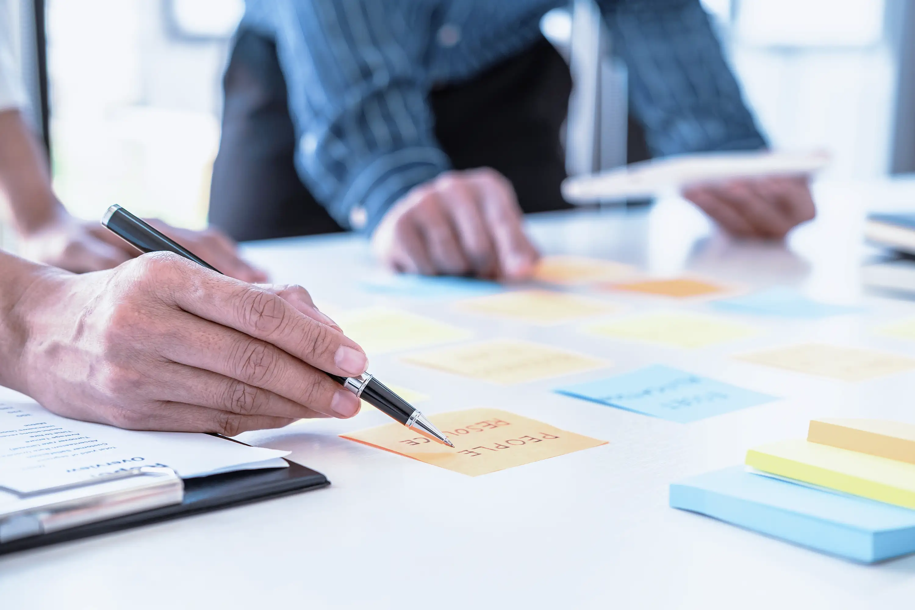 Colleagues reviewing sticky notes on a work table. 