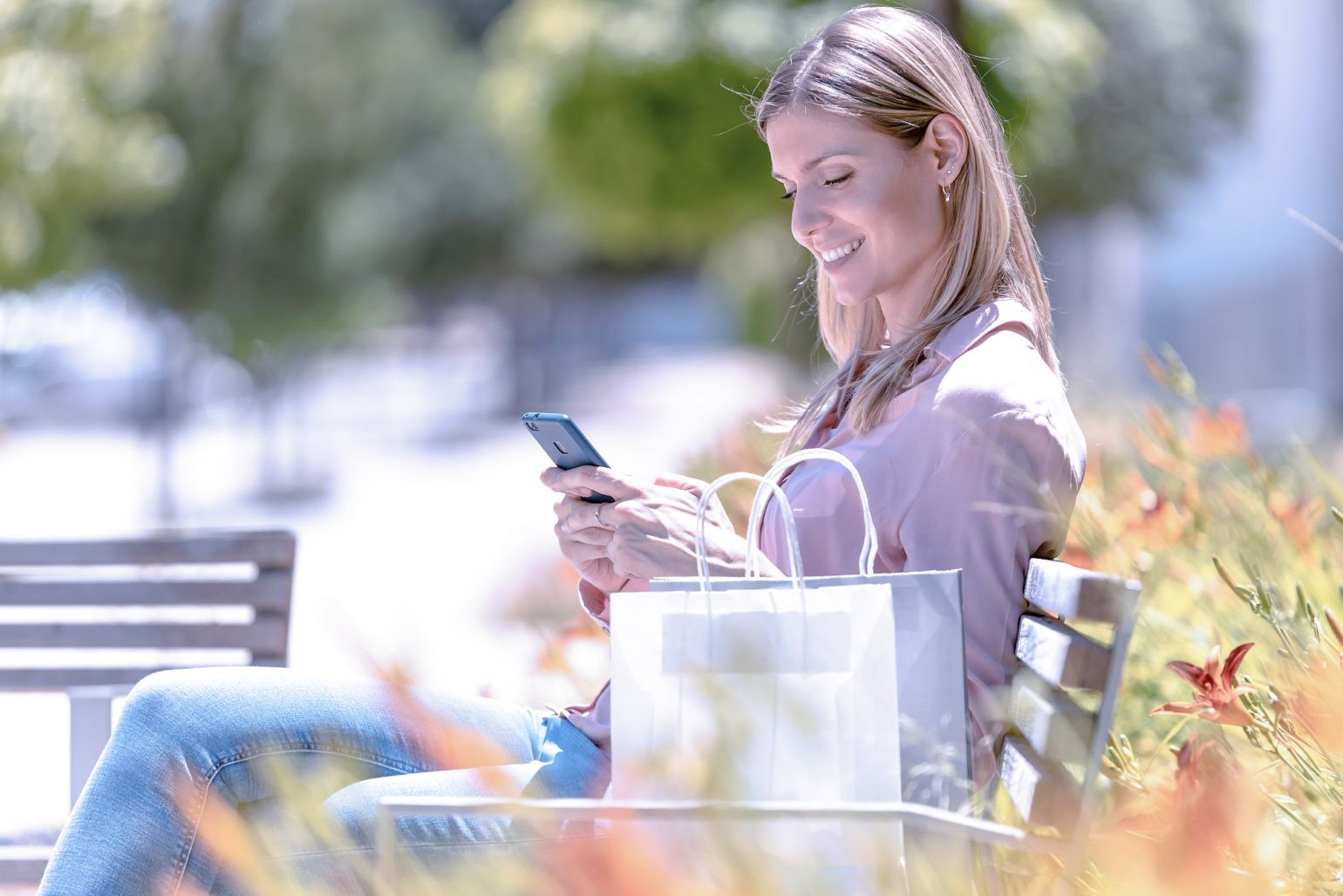 Woman browsing through a shop on smartphone outdoors.