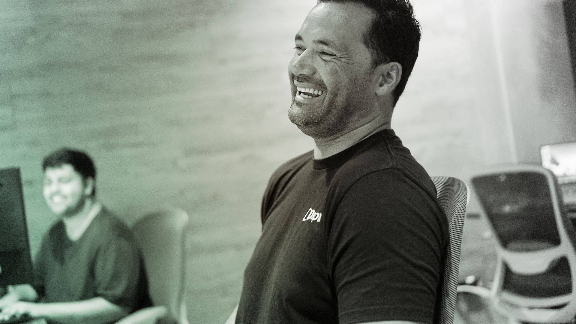 Photo of man smiling and laughing in workplace.