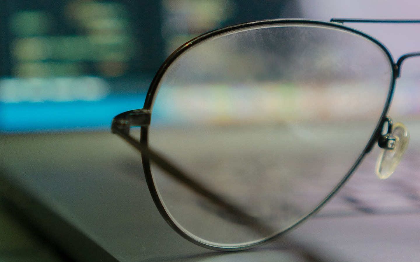 Close up photograph of glasses against a laptop, blurry background