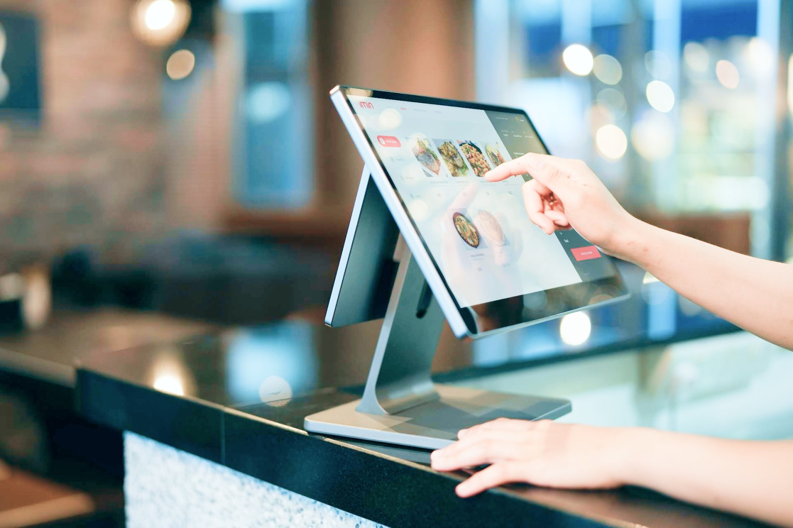 Worker's hands interacting with touchscreen kiosk.