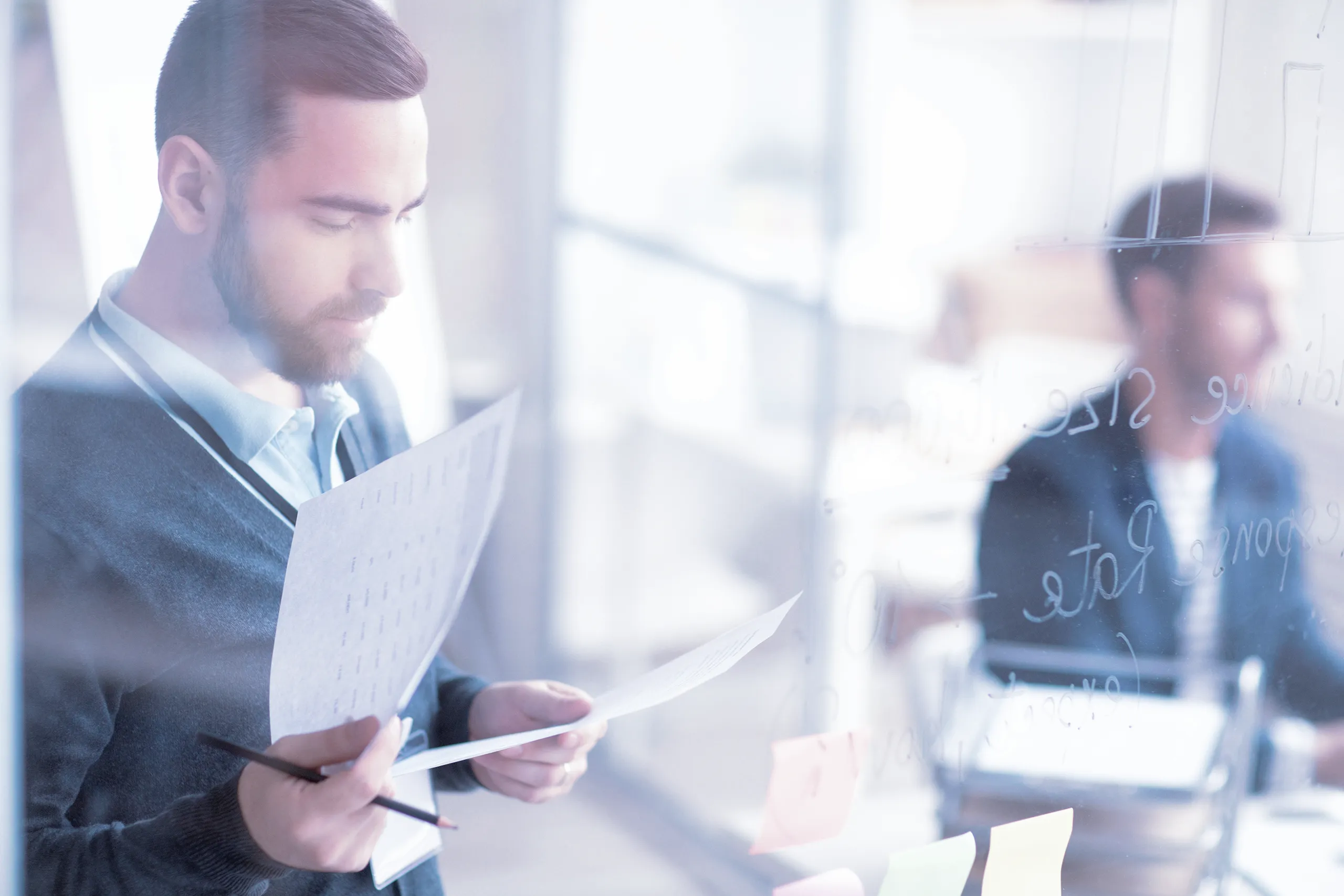 Team members against a window; with charts and drawings visible on the window. 