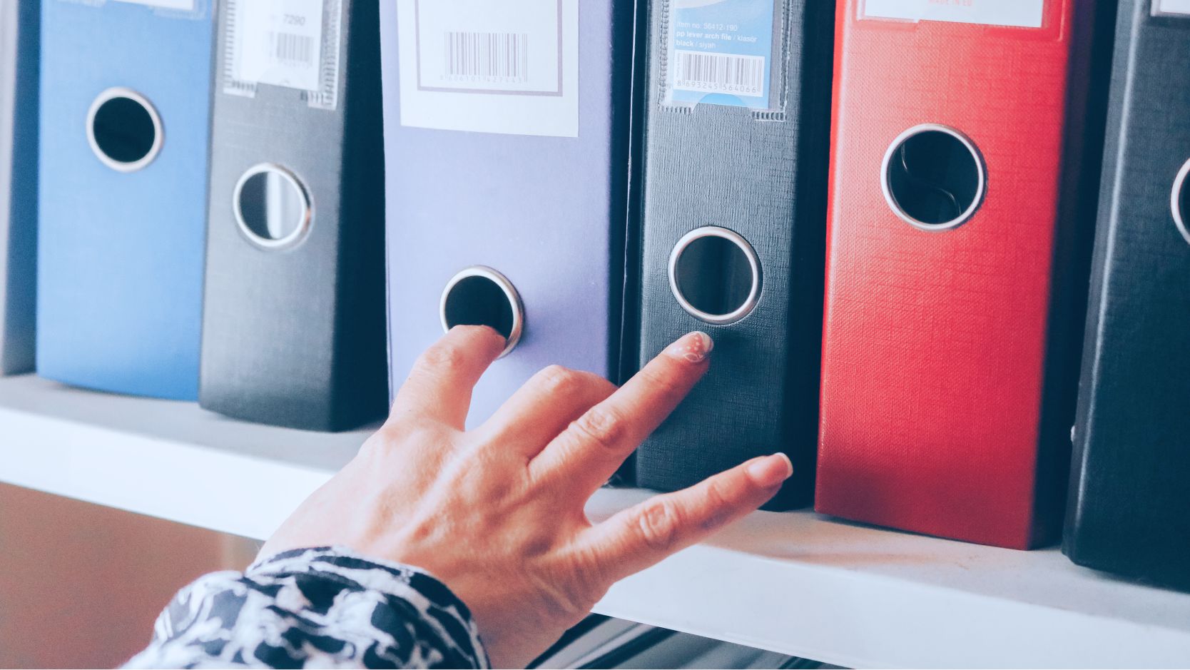 hand reaching for file folder in a cabinet