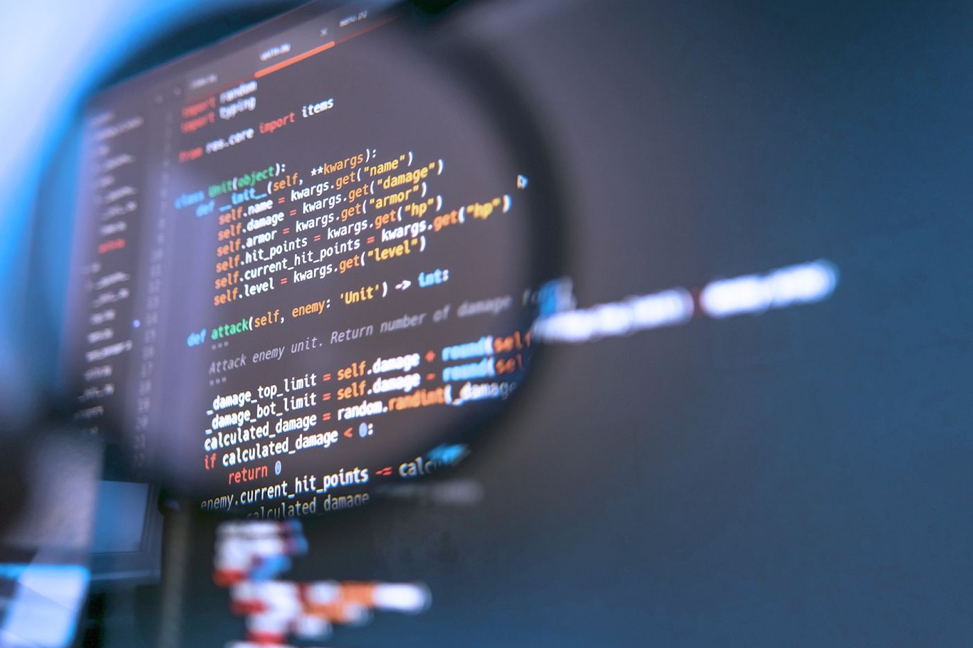 Magnifying glass showing a magnified portion of a computer code on laptop screen. 