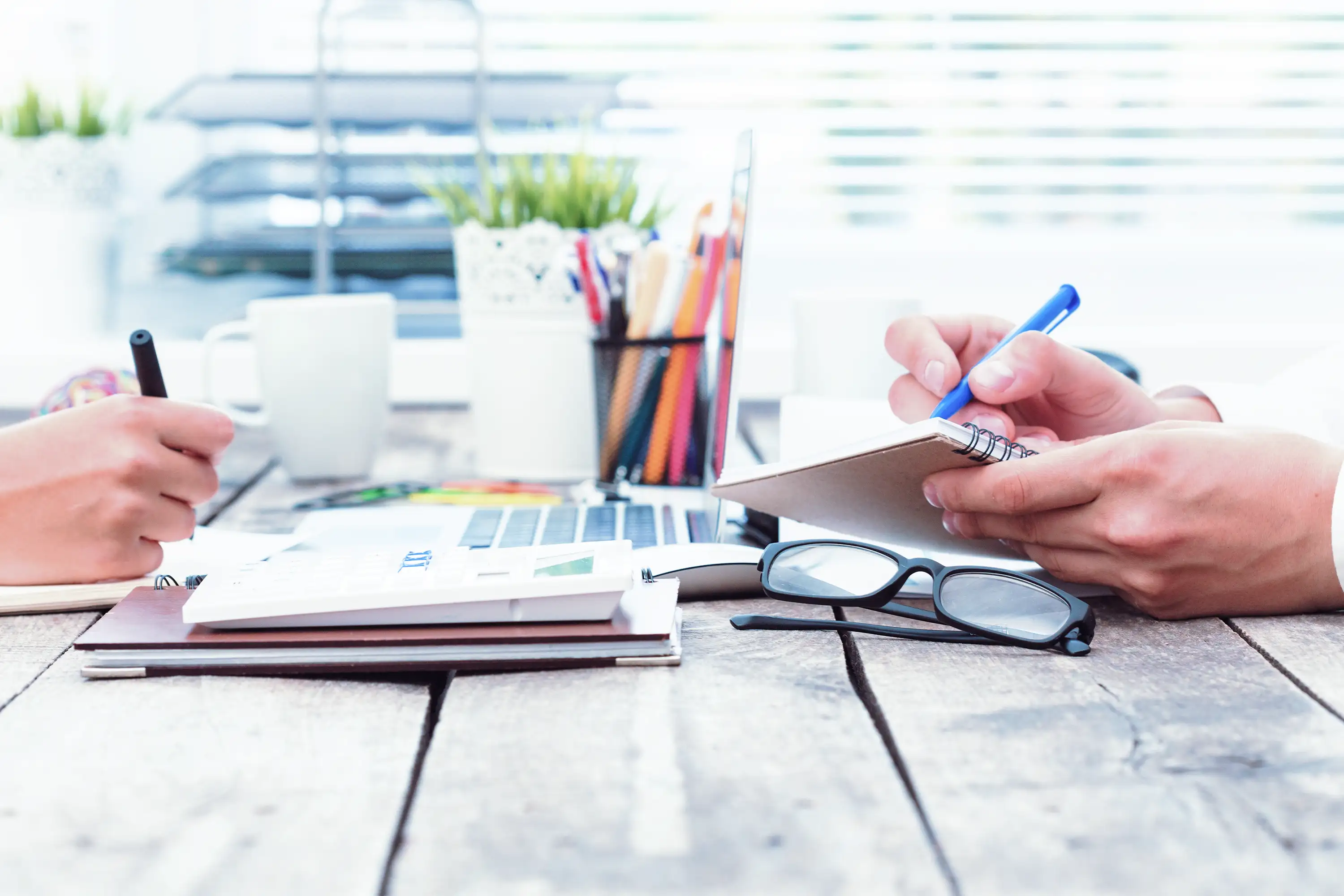 Colleages writing notes on a work bench.