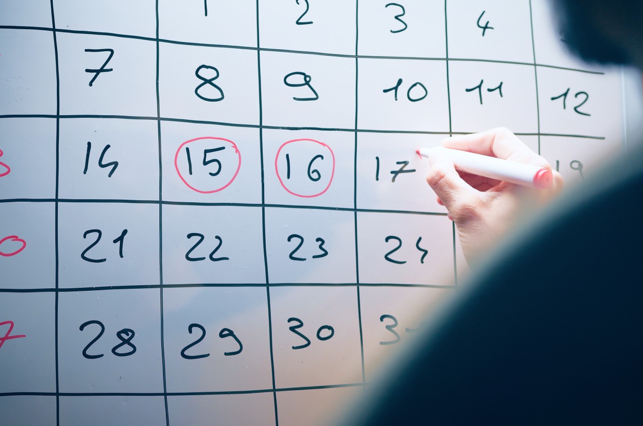 Employee circling key dates on a wall calendar