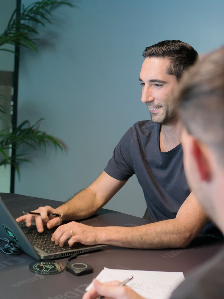 Two male staff in meeting, with laptop on desk