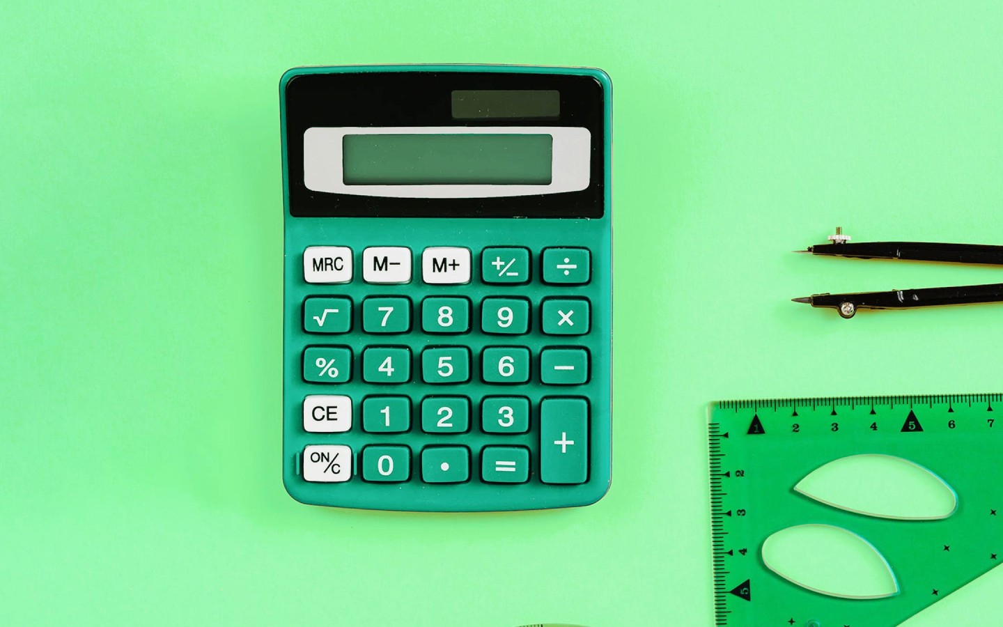 Calculator with protractor and measuring tool against green background