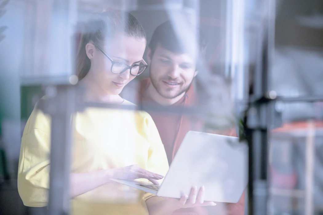 Window reflection of two colleagues working together.