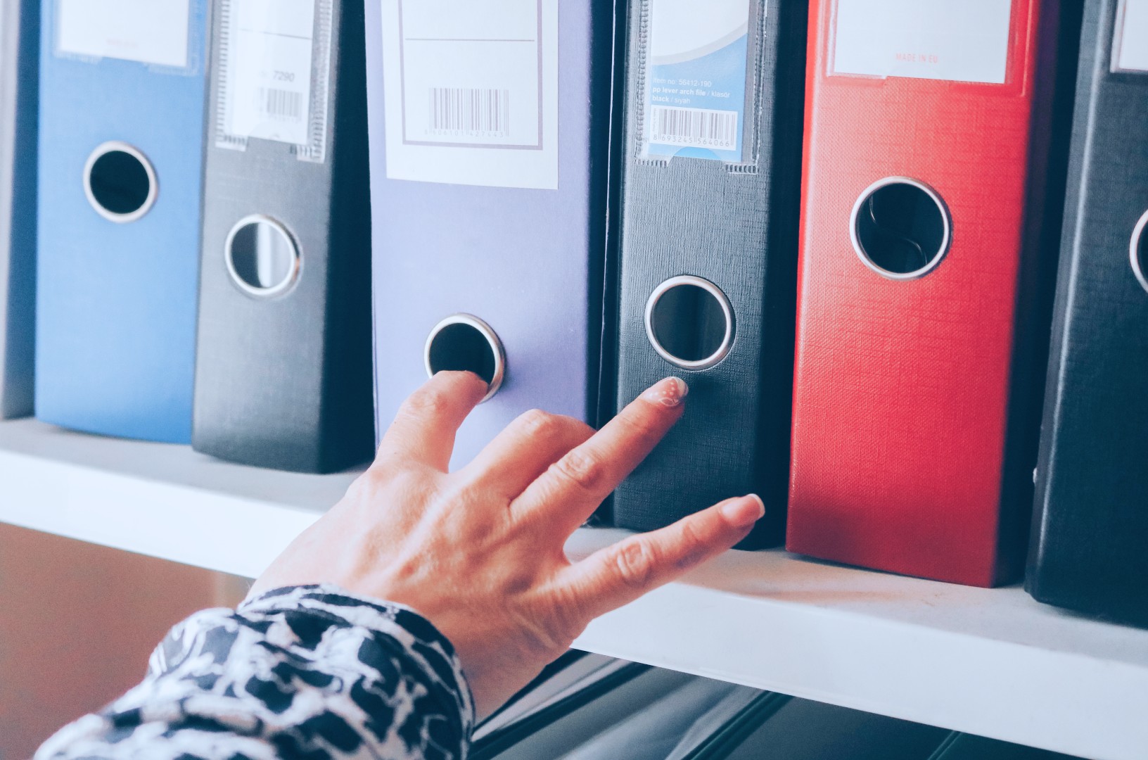 A hand reaching for file folders on a cabinet