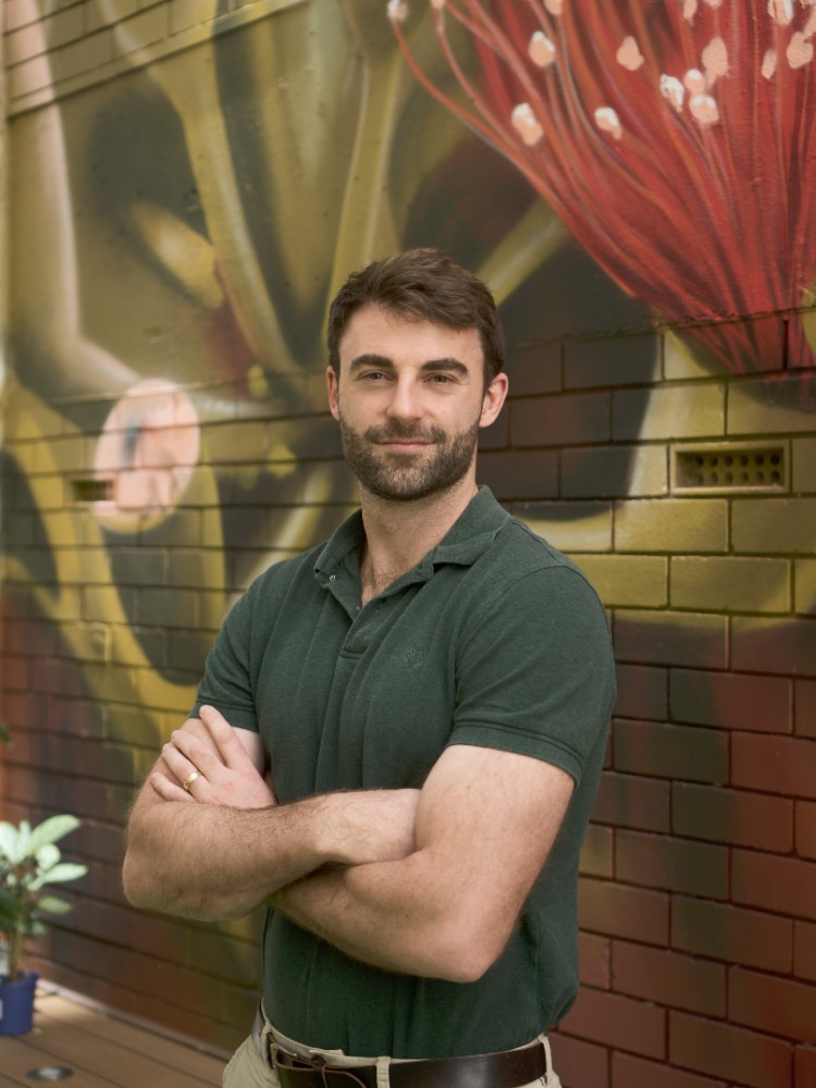 Image of man against illustrated-mural wall.