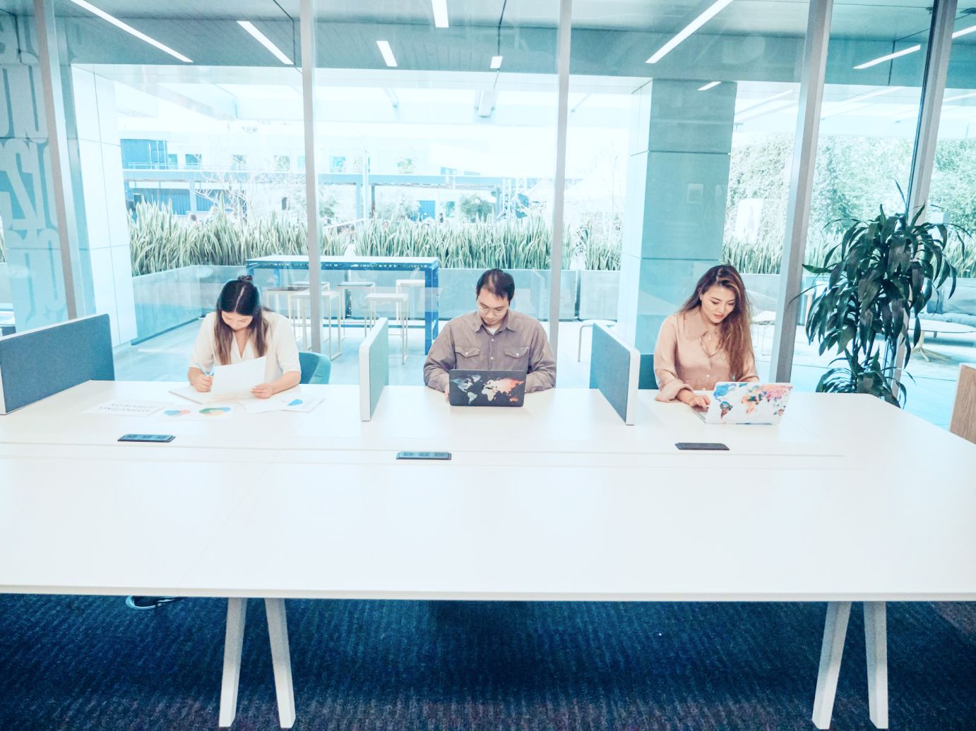 image of three colleagues working on large coworking table space