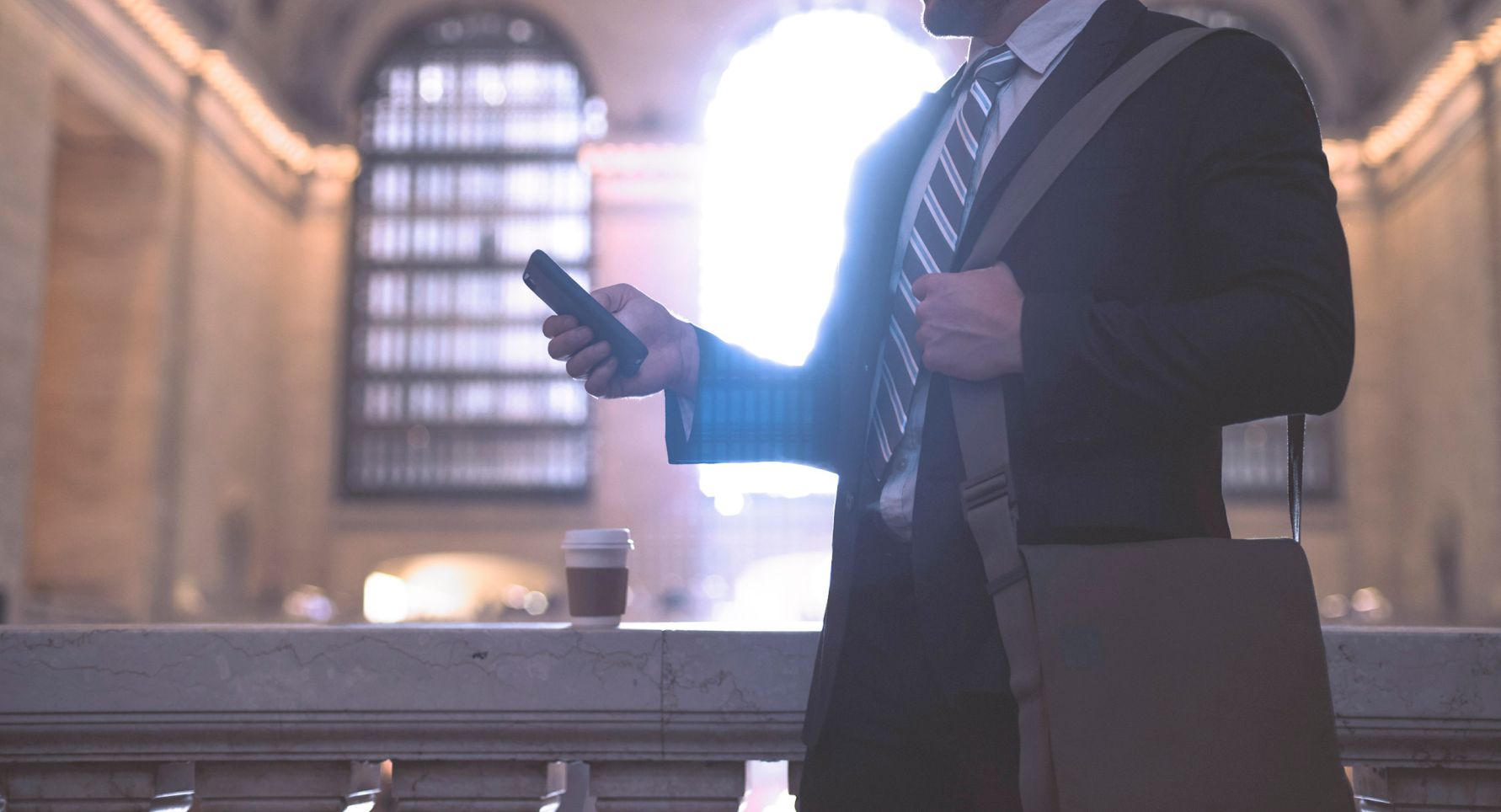 Man checking mobile phone in a train station.