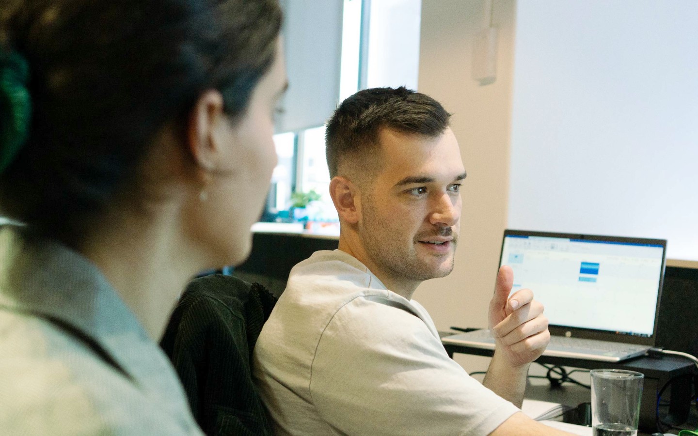 Female and male colleague discussing work, with laptop in background