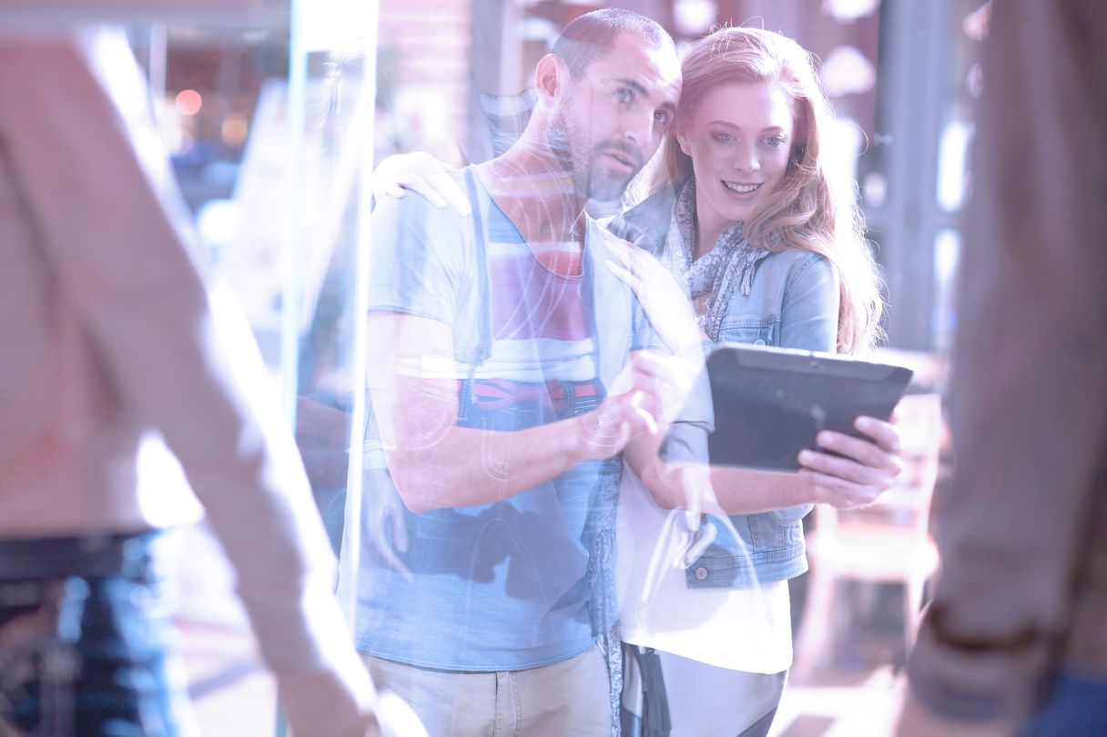 Young couple window shopping with a tablet.