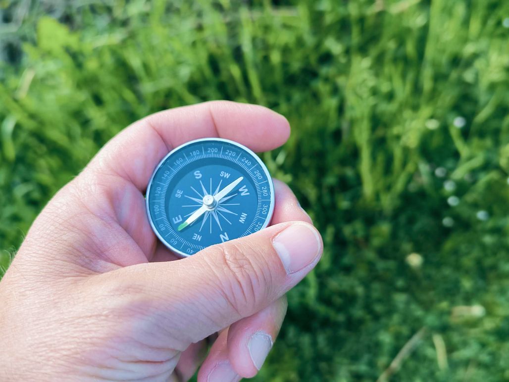 Hand holding a compass outdoors
