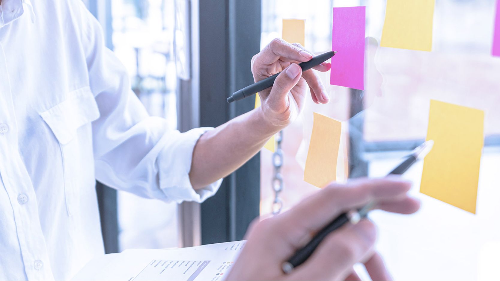 Colleagues in collaboration with sticky notes on window
