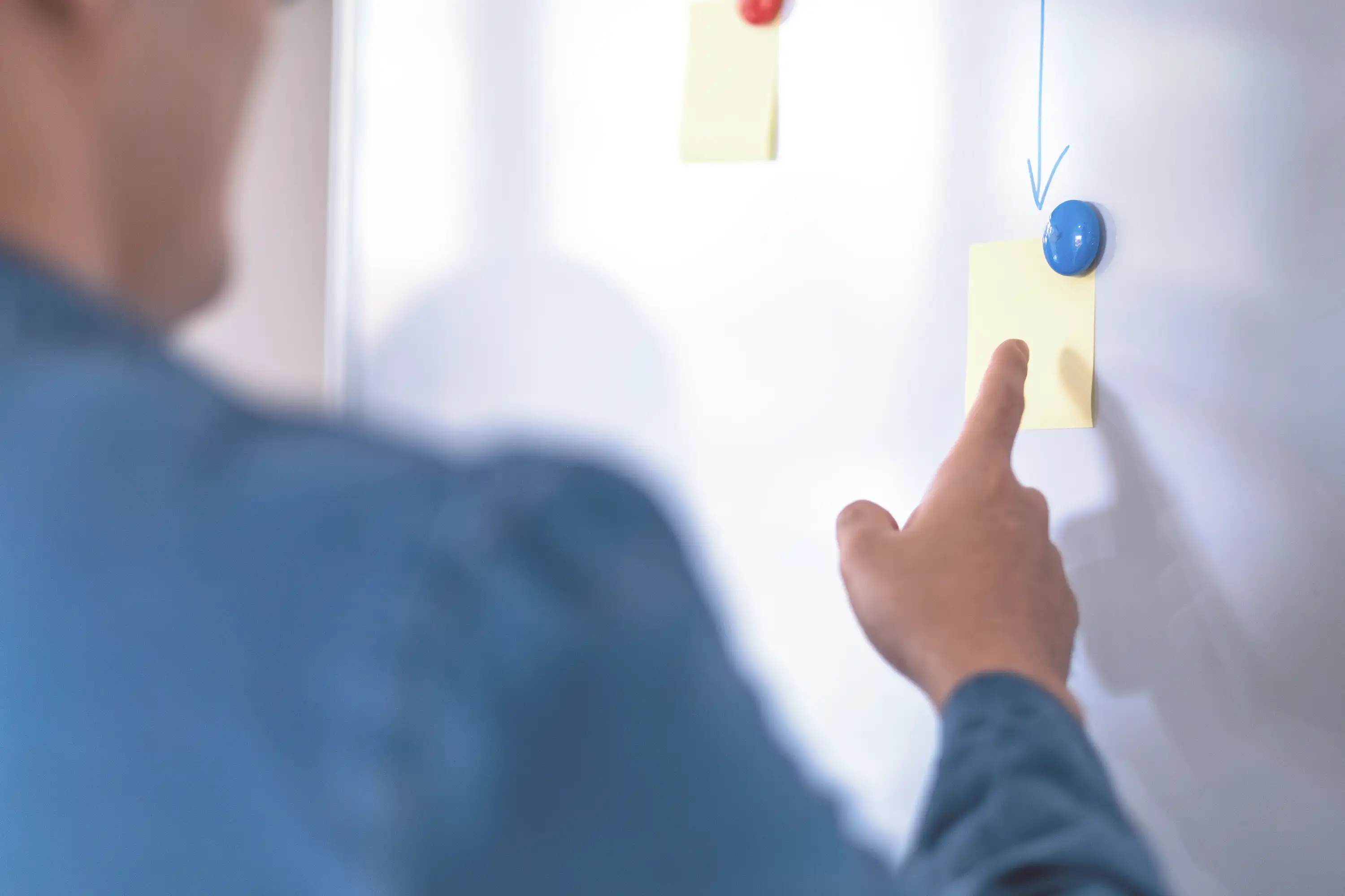 Businessman pointing at a sticky note on a whiteboard. 