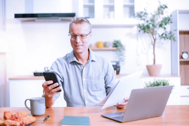 Man in a living room viewing messages on his smartphone. 