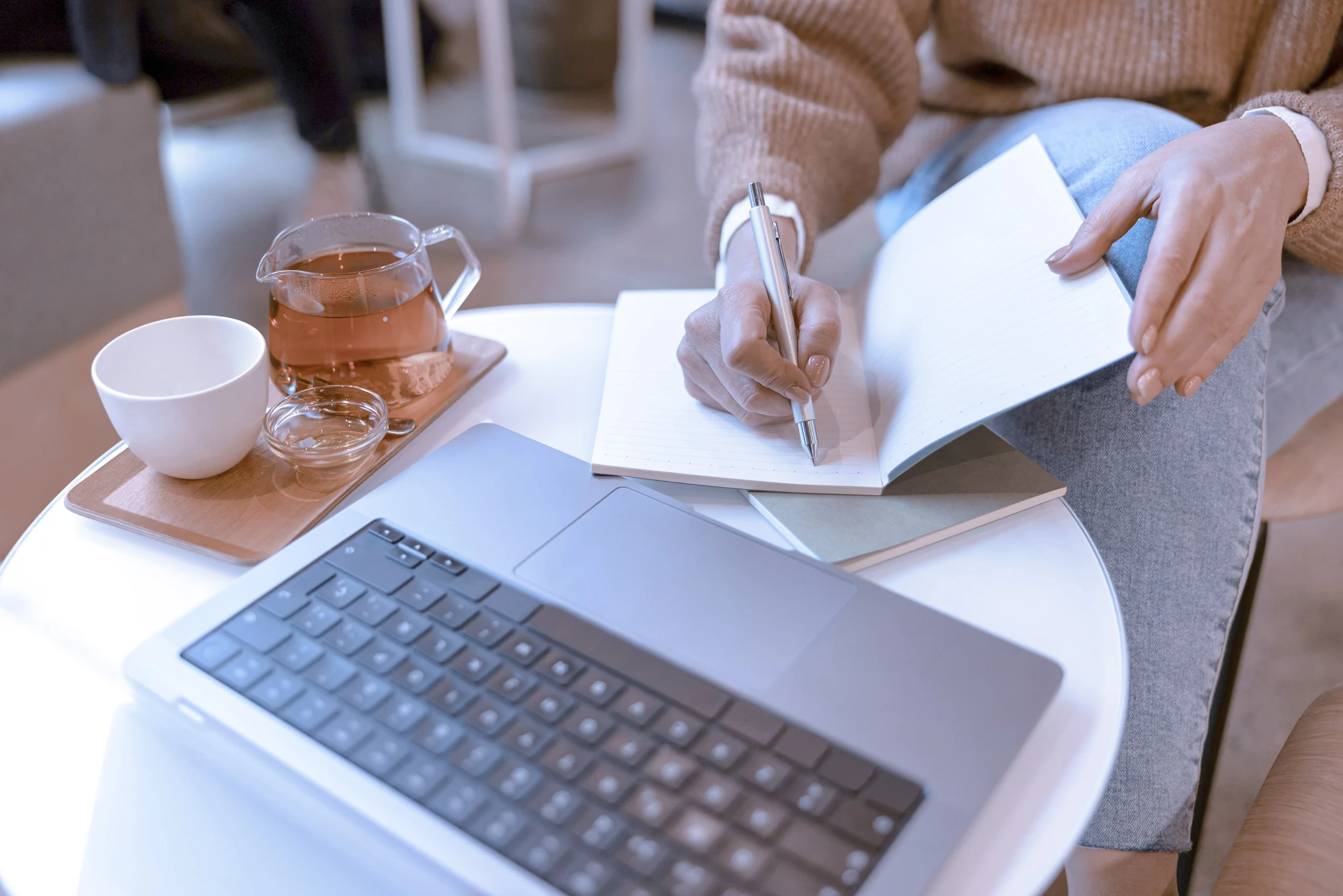 Woman making notes with laptop on a coffee table