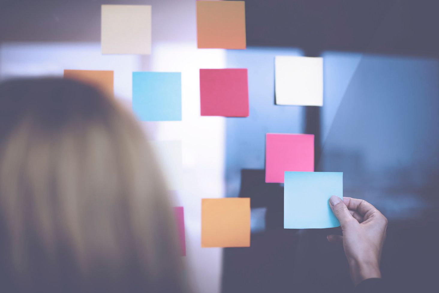 Woman planning a strategy with sticky notes on a window.