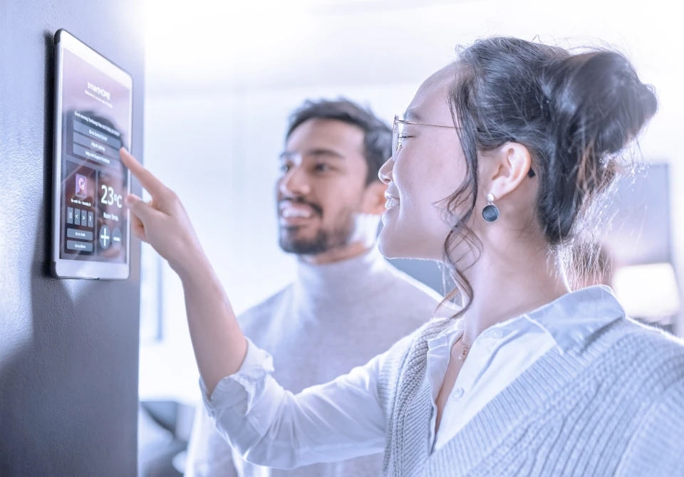 couple in living room interacting with user interface screen on an appliance.