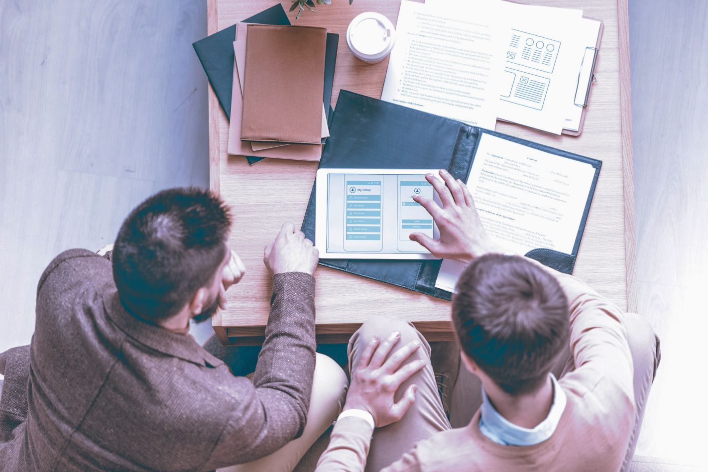 Developer and designer examining user interface on tablet.