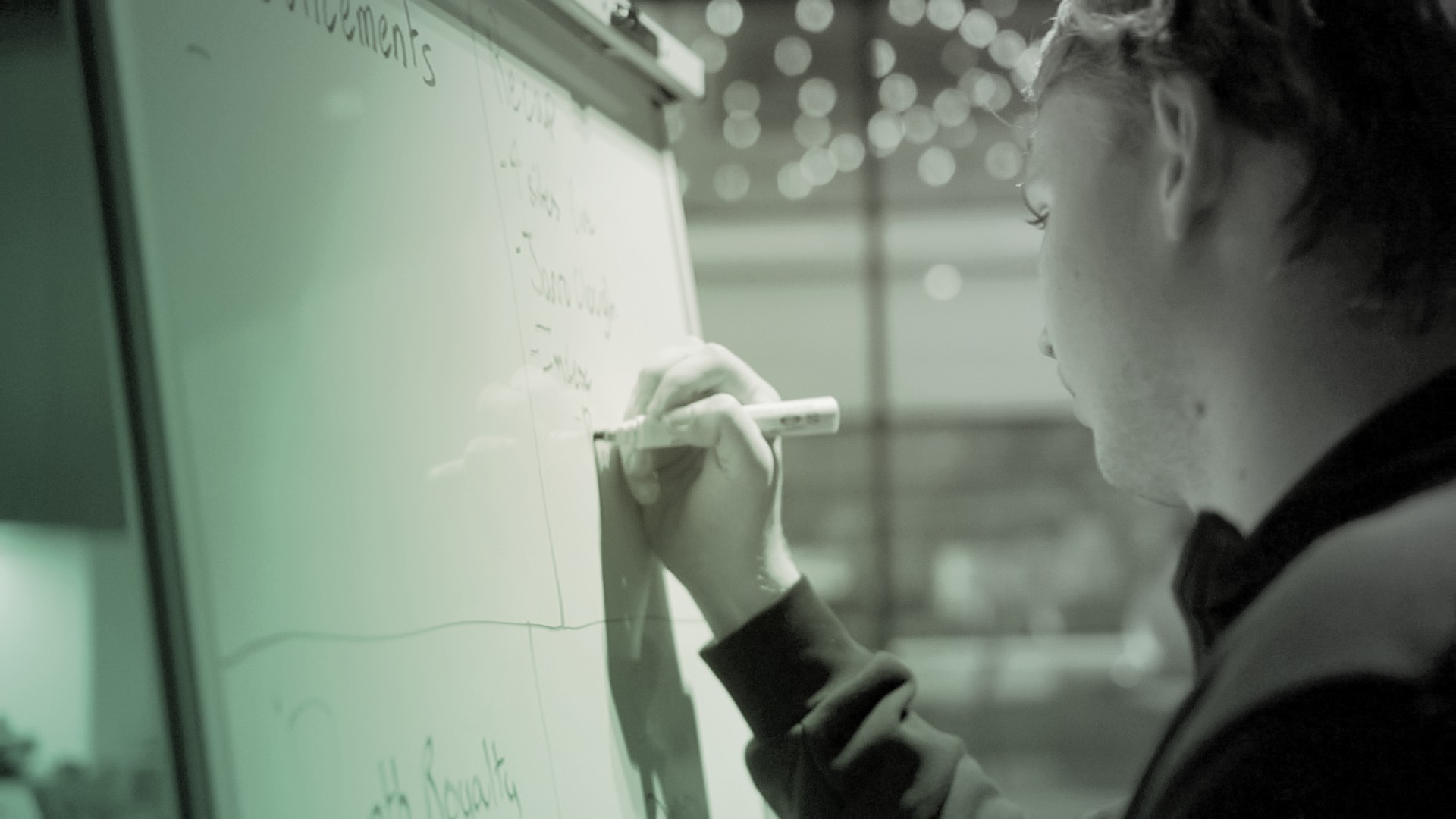 Image of man writing on whiteboard.