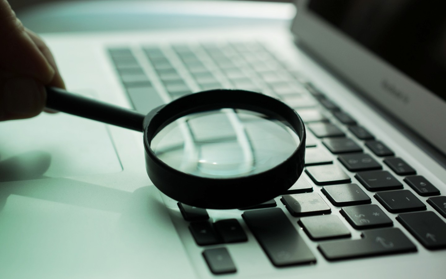 Magnifying glass resting on laptop keyboard