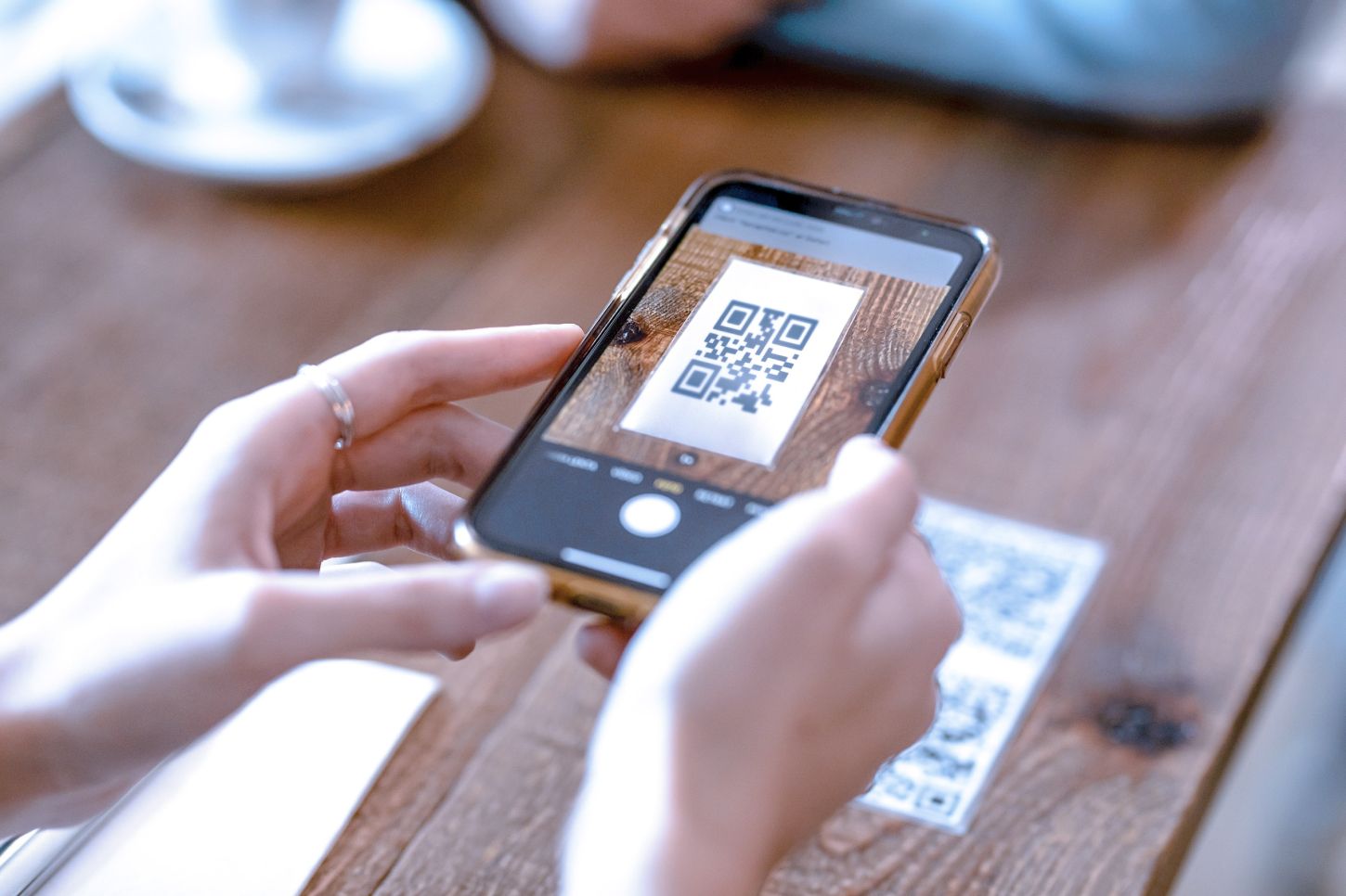 Close up of young woman hands using the smart phone to scan the qr code to select food menu in the restaurant.