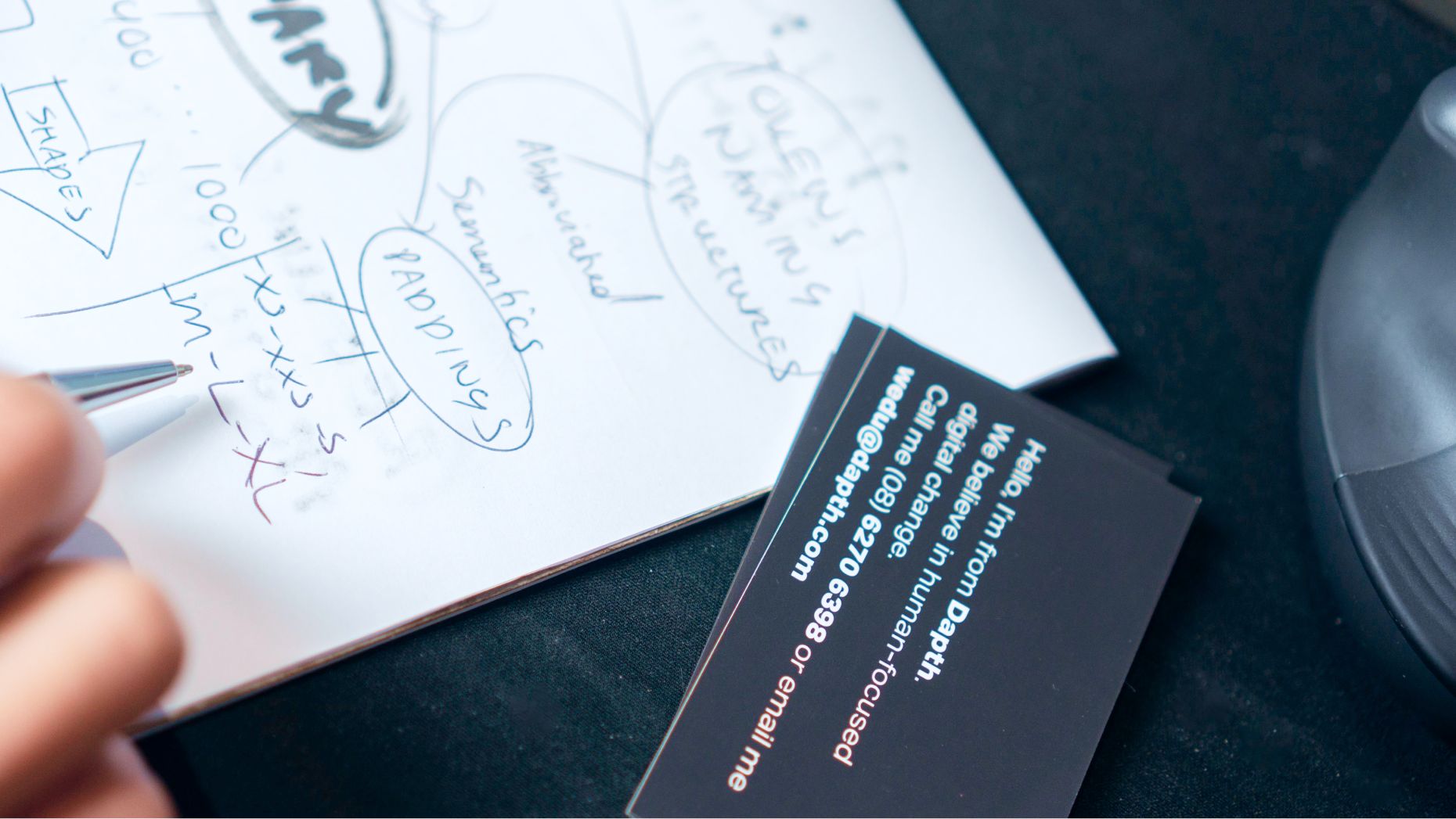 Close of up hand writing on a notepad with business cards on the foreground