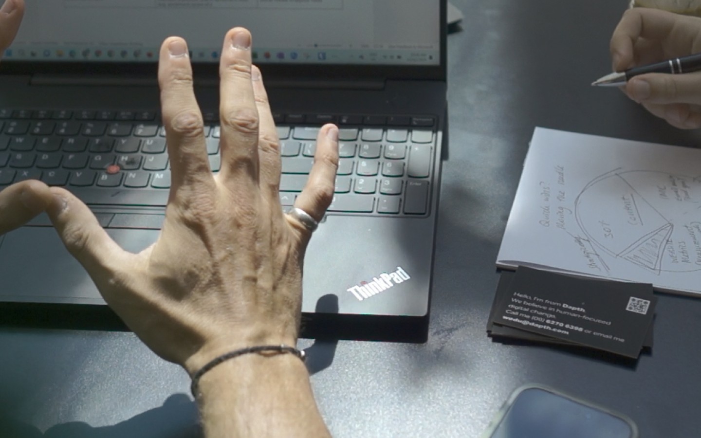 Two colleagues discussing work with laptop and notepad on table