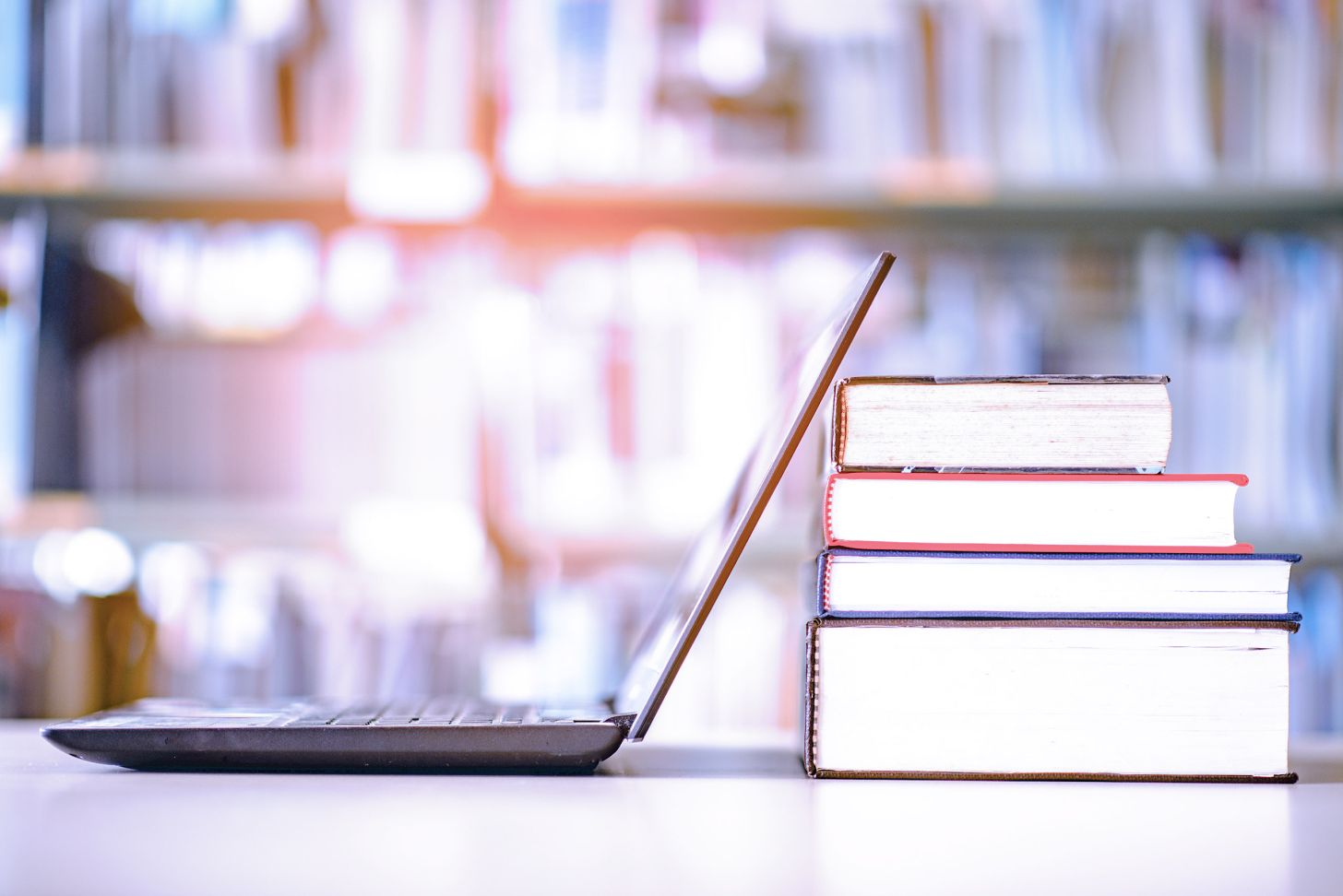 Image of laptop standing next to a stack of books. 