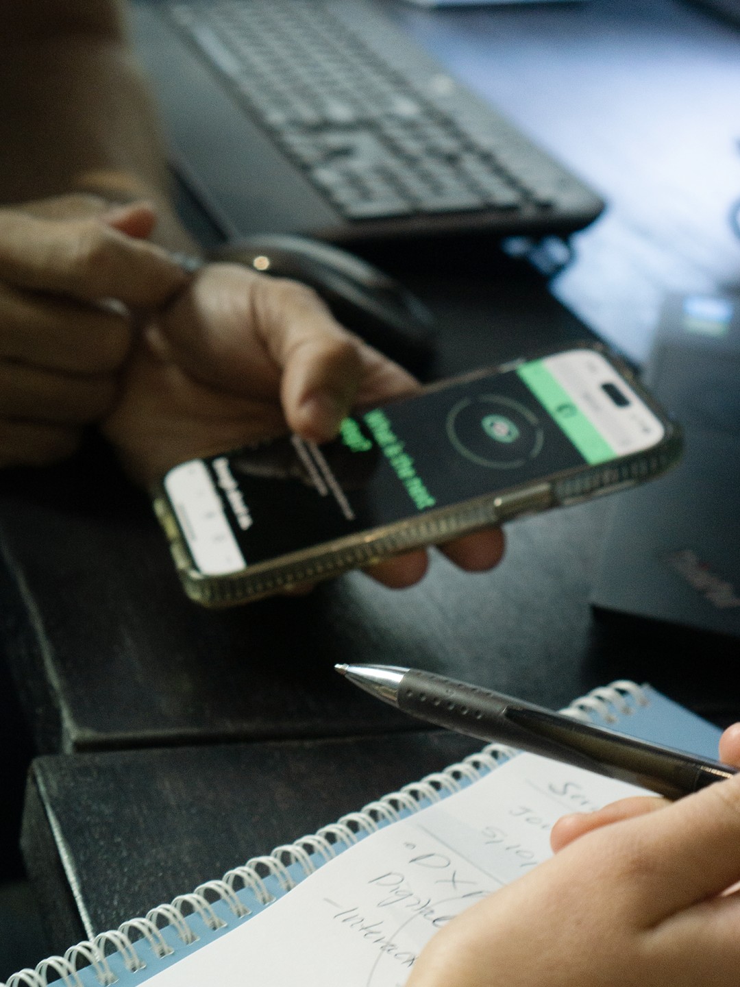 Two staff reading Dapth website on mobile, with paper and pen on desk